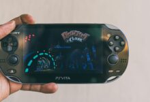 Close-up of a hand holding a PlayStation Vita with Ratchet & Clank displayed on screen. Captured in Johannesburg.
