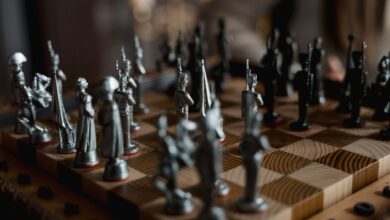 Detailed close-up of metallic chess pieces on a wooden board, showcasing a strategic game in progress.