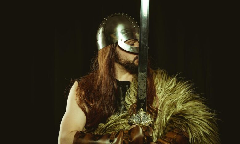 A medieval warrior in full armor, wearing a helmet and holding a large sword.
