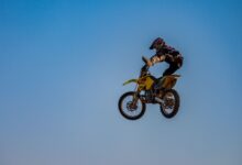 Dynamic motocross jump featuring a rider in full gear under a clear sky.