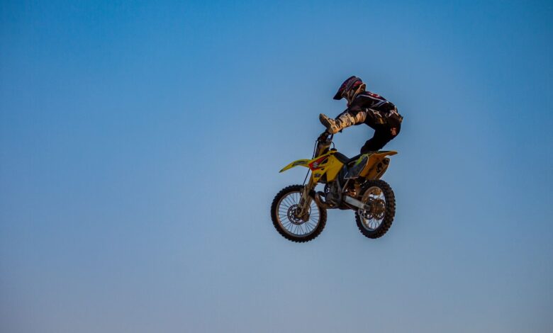 Dynamic motocross jump featuring a rider in full gear under a clear sky.