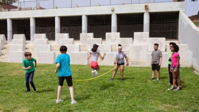 Group of children enjoying a jump rope game outdoors in a sunny park.
