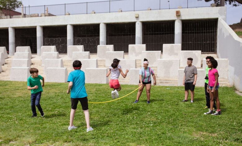 Group of children enjoying a jump rope game outdoors in a sunny park.