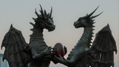 Two impressive dragon sculptures holding an enigmatic egg against a twilight sky, symbolizing fantasy and myth.
