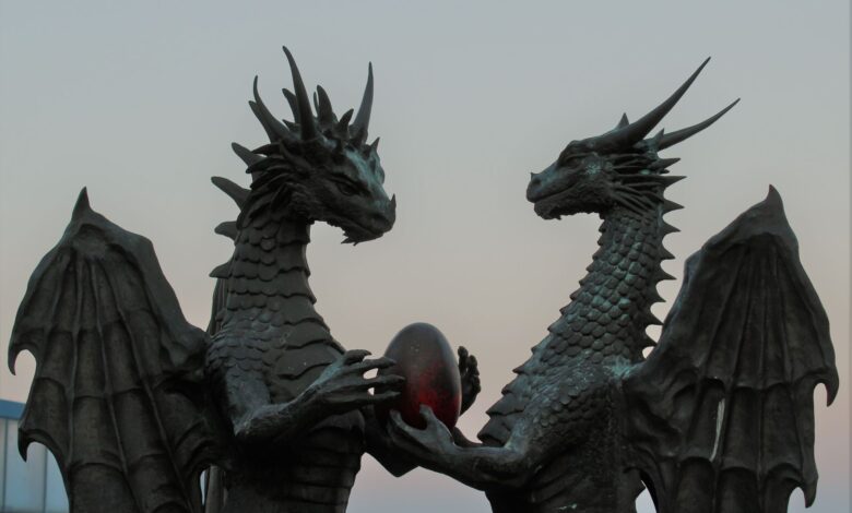Two impressive dragon sculptures holding an enigmatic egg against a twilight sky, symbolizing fantasy and myth.