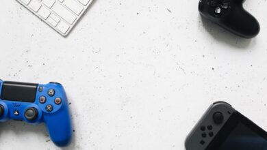 A variety of game controllers and a keyboard arranged on a white textured surface, offering a minimalist gaming setup.