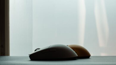 Silhouette of two wireless computer mice against a soft background, highlighting modern technology design.