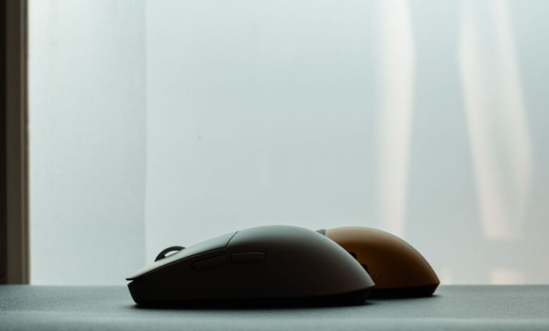 Silhouette of two wireless computer mice against a soft background, highlighting modern technology design.