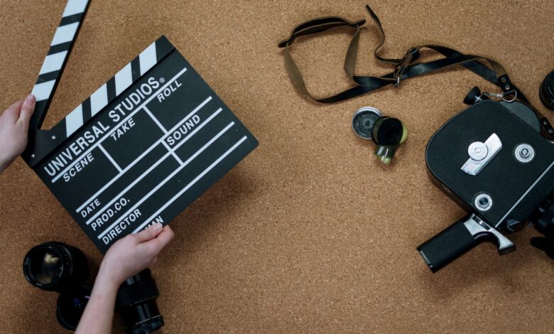 Top view of vintage film camera and clapperboard on cork background, evoking old cinema vibes.