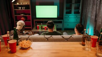 Three friends sitting on a couch playing video games together in a cozy living room setting.