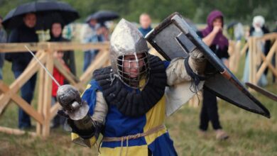 A knight in full armor engaged in a lively medieval reenactment outdoors.