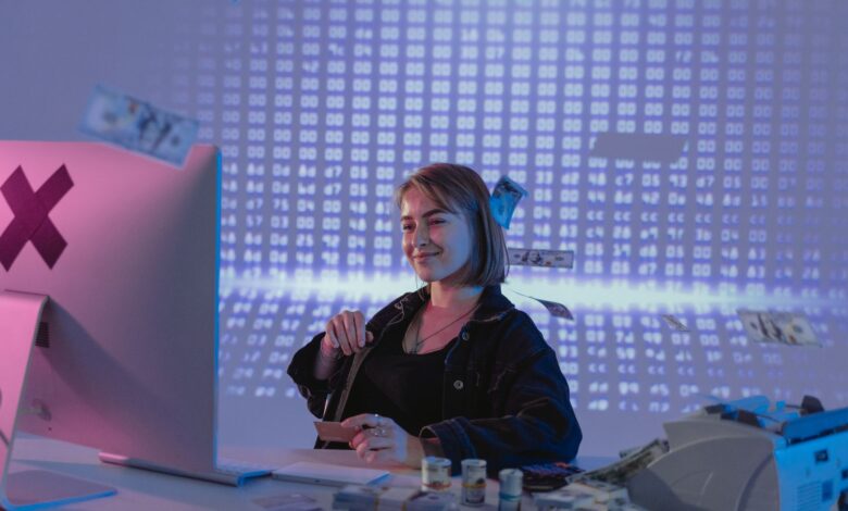 Smiling woman surrounded by digital and physical currency in a tech office setting.