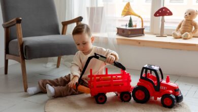 A young child playing with a red toy tractor indoors, surrounded by cozy decor.