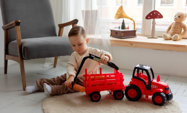 A young child playing with a red toy tractor indoors, surrounded by cozy decor.