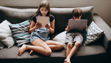 Two children engaging with tablets on a sofa, creating a modern lifestyle scene.