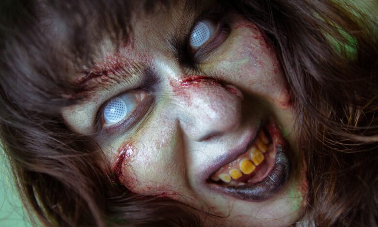 Frightening close-up of a zombie with white eyes and gory makeup, perfect for Halloween themes.