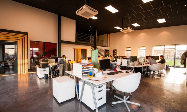 A spacious and modern open-plan office with natural lighting and employees working at desks.