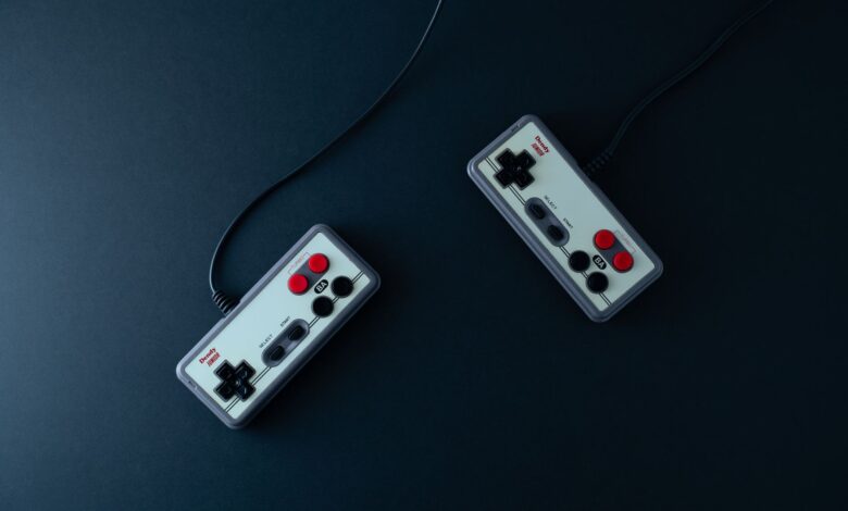 Top view of two retro gaming controllers on a minimalist dark background.