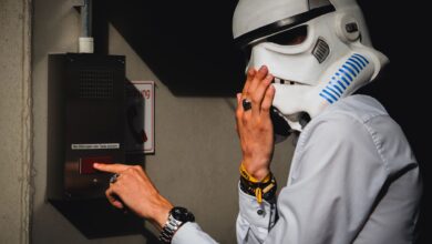 A person wearing a Stormtrooper helmet interacts with an intercom in an indoor setting.