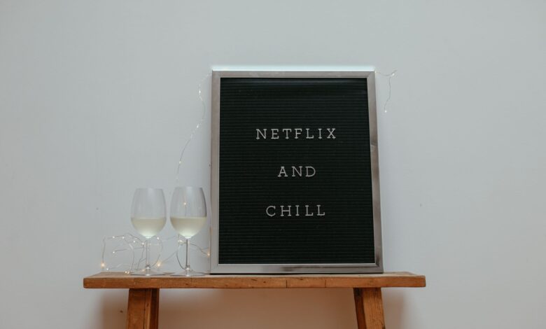 Minimalist scene with a 'Netflix and Chill' board and wine glasses on a wooden stool.