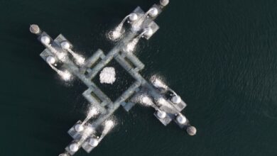 Aerial shot showing a geometric industrial platform over a body of water.