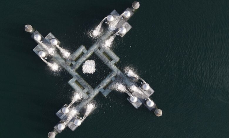 Aerial shot showing a geometric industrial platform over a body of water.