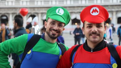 Two men in Mario and Luigi costumes smiling at a cosplay event.