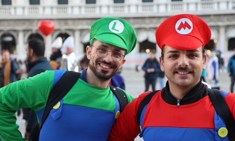 Two men in Mario and Luigi costumes smiling at a cosplay event.