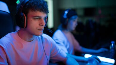 Man with headset engaged in intense gaming session under neon lights.