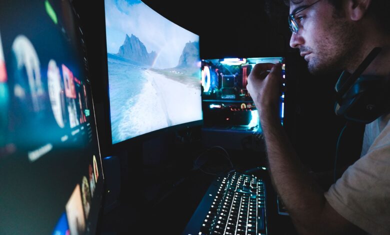 A man in eyeglasses focused on multiple screens, showcasing modern technology setup.