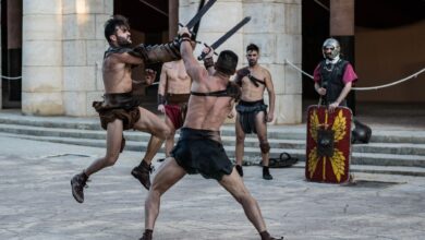 Intense scene of gladiators engaging in combat with swords in an ancient-style arena.