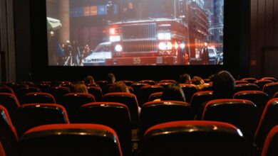 People seated in a cinema watching a movie on a large screen.