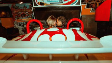 A couple having fun at an arcade, enjoying a racing game together with a lighthearted mood.