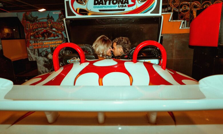 A couple having fun at an arcade, enjoying a racing game together with a lighthearted mood.