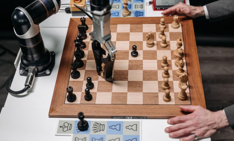 A robotic arm playing chess against a human hand on an electronic chessboard indoors.