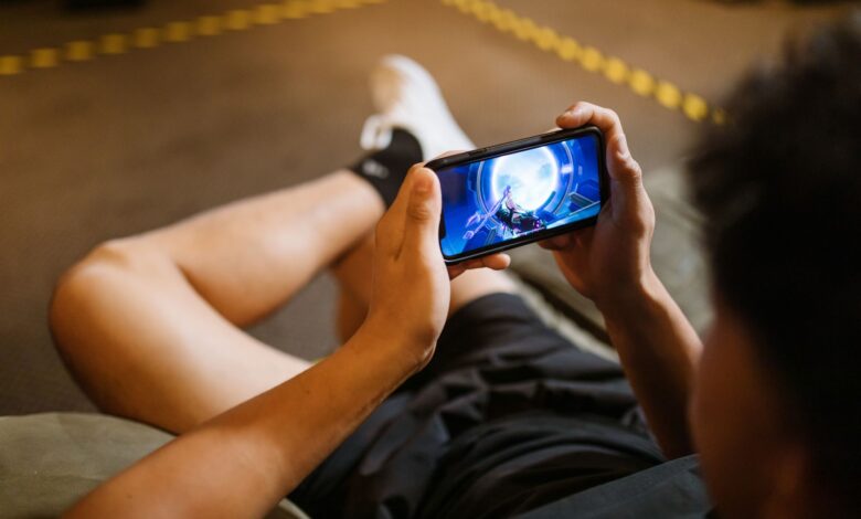 Man playing a video game on a smartphone while sitting comfortably indoors.