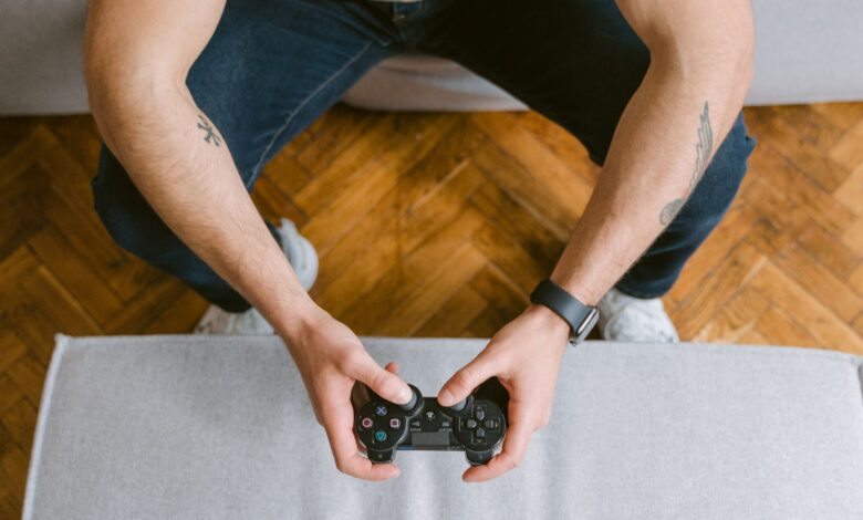 A man sitting on a couch holds a game controller, ready to play video games.