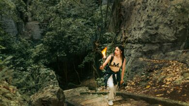 Young woman exploring dense forest with a torch, capturing an adventurous spirit.