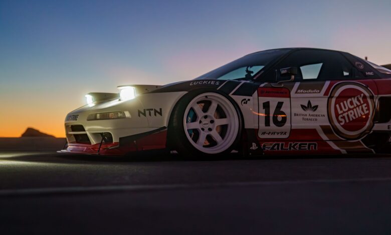 A sleek racing car with branded decals against a vibrant sunset backdrop on an open road.