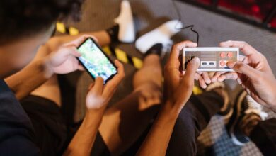 Close-up of teenagers playing mobile and retro video games indoors, showcasing fun and technology.