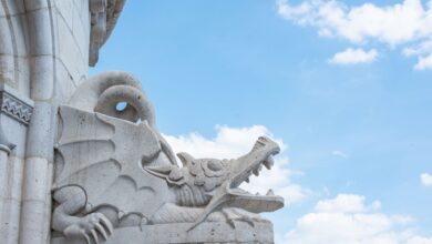 Close-up of an intricate stone dragon sculpture set against a clear blue sky.