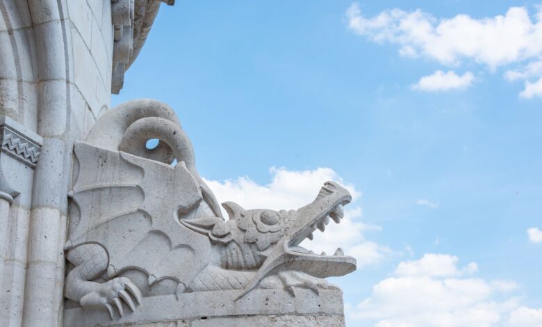 Close-up of an intricate stone dragon sculpture set against a clear blue sky.