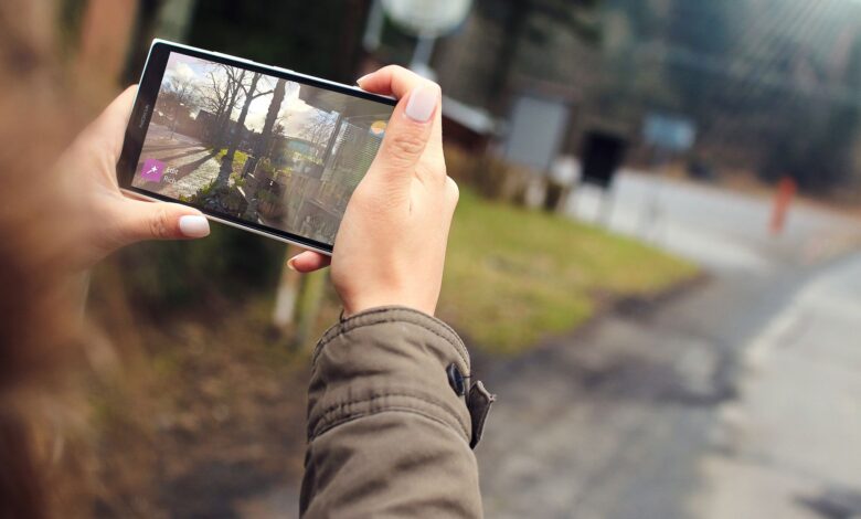Woman capturing outdoor scenery using a smartphone. Close-up of hands holding the device.