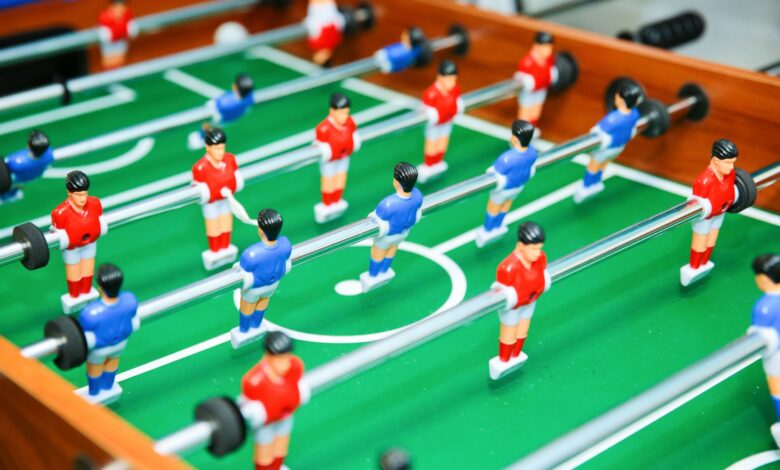 Vibrant foosball table game in play, showcasing red and blue teams in strategic setup.