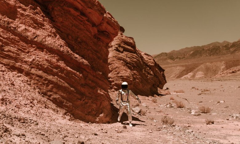 An astronaut in a spacesuit explores a barren, eroded desert, resembling Martian terrain.