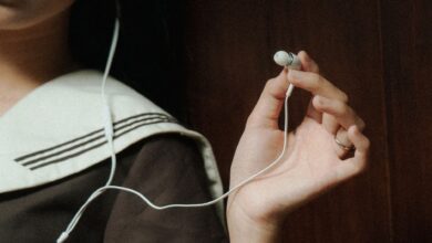 A close-up image of a hand holding earphones next to a person wearing navy attire, suggesting a relaxed mood.