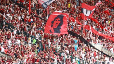 Excited soccer fans in red and black cheer at Maracanã Stadium, Rio de Janeiro.