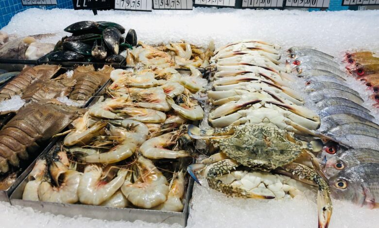 Close-up of fresh seafood including shrimps, crabs, and fish on ice at a market.