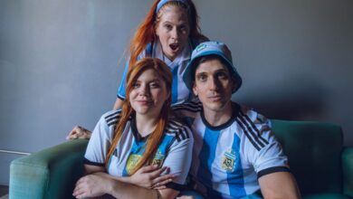 Group of fans in Argentina soccer jerseys expressing excitement indoors.