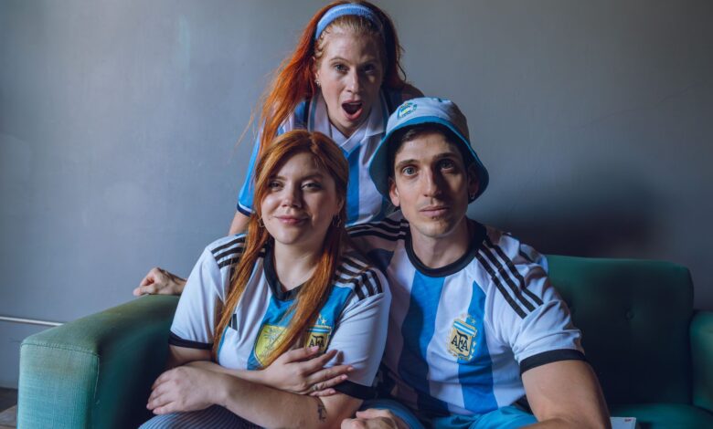 Group of fans in Argentina soccer jerseys expressing excitement indoors.